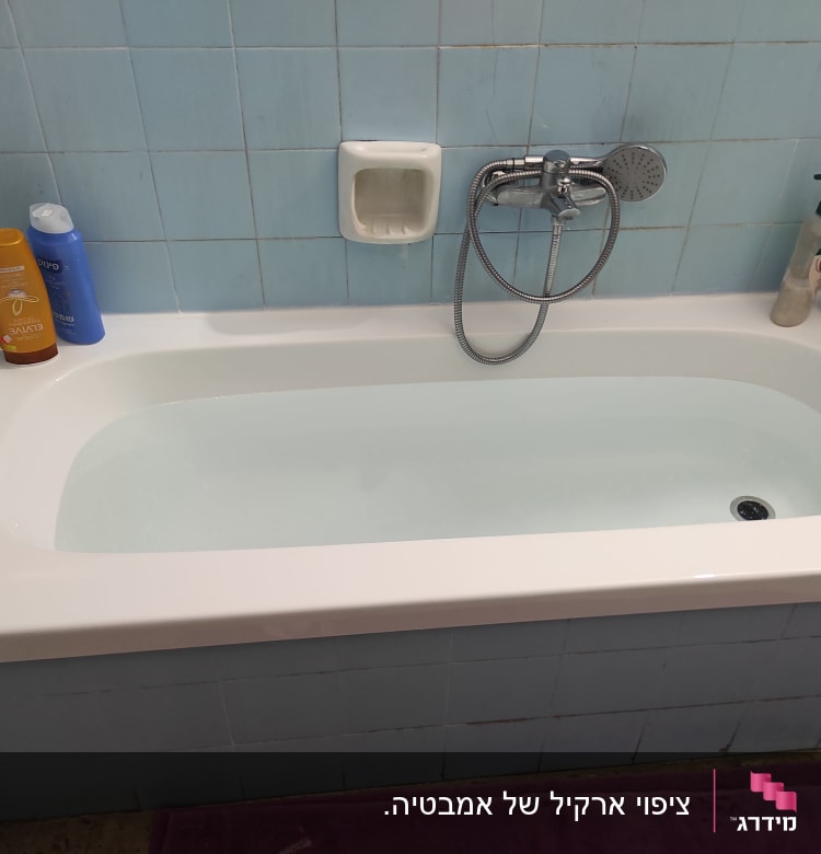 אמבטיה עם אריחים כחולים, ברז ומוצרי טיפוח